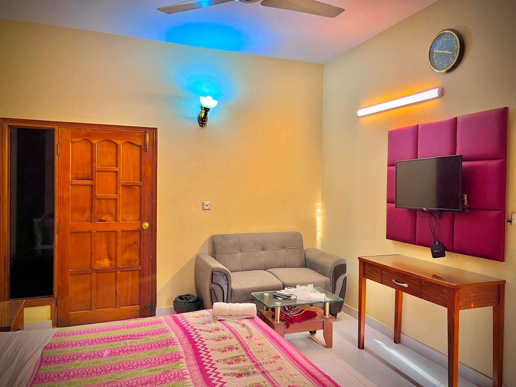 Deluxe Room with pink headboard, sofa and flat-screen TV